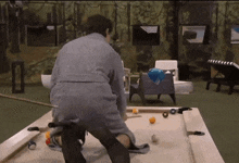 a man in a robe is playing pool in a room