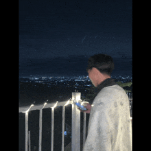 a man stands on a balcony looking at his phone