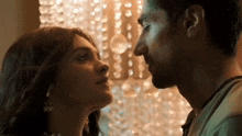 a man and a woman are kissing each other in front of a chandelier .