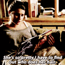 a woman is sitting on a couch reading a book and says she 's so pretty