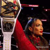 a woman in a red outfit is holding up a wrestling belt