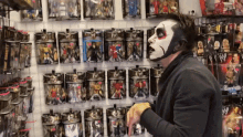 a man wearing a mask is standing in front of a wall of action figures including one that says smackdown