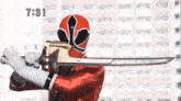 a man in a red helmet is holding a large sword in front of a building .