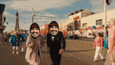 a group of people are walking down a street and one of them is wearing a hat that says websiteol
