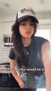 a woman wearing a hat and a necklace says this song live would be so fun ..