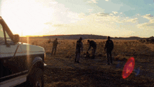 a group of people are standing in a field near a van