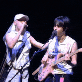 a man singing into a microphone next to a man playing a guitar with a strap that says balenc on it