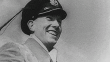 a black and white photo of a man in a hat laughing