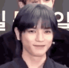 a close up of a person 's face with a ponytail and a smile on their face .