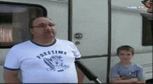 a man wearing a freetime t-shirt stands next to a boy