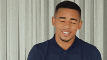 a young man with his eyes closed is wearing a blue polo shirt .