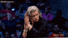 a woman with pearls on her wrist stands in front of a crowd and says thekamdreesen