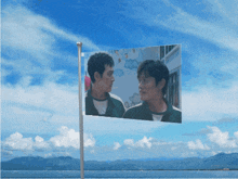 a flag with a picture of two men on it is flying in the wind