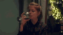 a woman drinking from a wine glass with the hashtag #flack visible