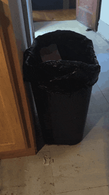 a black trash can sitting on a tiled floor
