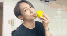 a young man in a black shirt holds a yellow object in his hand