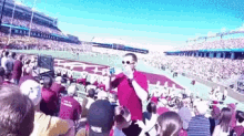 a man is holding a child in his arms in a stadium while a crowd watches .