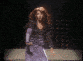 a woman in a purple dress dancing on a stage