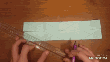 a person is cutting a piece of paper with a ruler and a pencil and the words made in animotica are visible