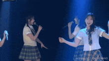 two girls singing into microphones on a stage with akb48 live on demand written on the bottom