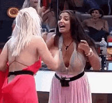 two women are standing next to each other in a room and talking .