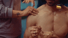 a man without a shirt is being touched by a woman with a sony logo on the bottom