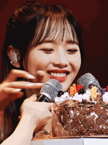 a woman is holding two microphones in front of a chocolate cake