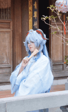 a woman in a blue wig holds a fan in front of a building with chinese writing