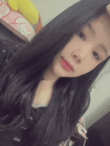 a girl with long black hair is taking a selfie in a bedroom