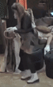 a woman is standing in a room with a suitcase and a bag .