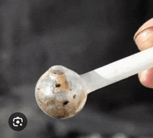 a person is holding a dirty glass pipe with a hole in the middle .