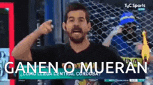 a man in a black shirt is pointing at the camera with the words ganen o mueran on the screen behind him