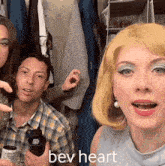 a group of people are posing for a picture and one of them is wearing a wig that says bev heart