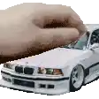 a hand is holding a white car in front of it .