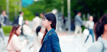 a woman in a blue jacket is walking down a street .