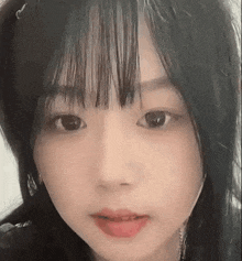 a close up of a woman 's face with long black hair and bangs .