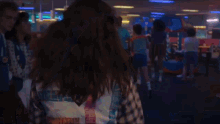 a woman is sitting at a table in a bowling alley with a crowd of people in the background .