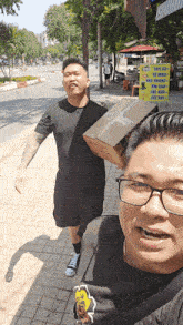 a man carrying a box on his head is standing next to another man