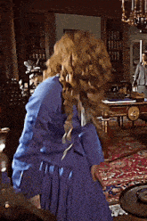 a woman in a blue dress is standing in a room