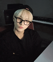 a young man wearing glasses and a black hat with the word supreme on it