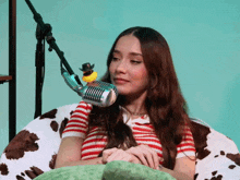 a woman sits in front of a microphone with a rubber duck in a cowboy hat