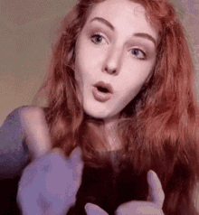 a woman with red hair is making a surprised face and giving a thumbs up