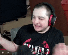 a man wearing headphones and a black shirt with the word cheer on it is laughing .