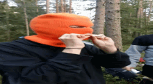 a person wearing an orange ski mask is holding something in their hands