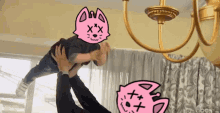 a person is holding a child in the air with a pink cat face on their head