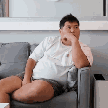 a man is sitting on a couch with his hand on his mouth