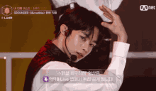 a man wearing a microphone and a white shirt is on a stage with a mnet logo in the corner