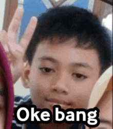 a young boy giving a peace sign with the words oke bang written below him