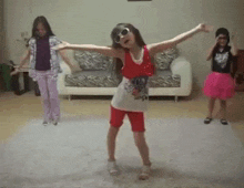 three little girls are dancing in a living room with their arms outstretched .