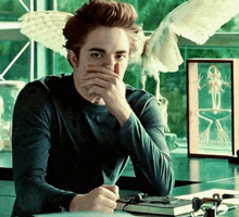 a man sits at a desk with his hand over his mouth